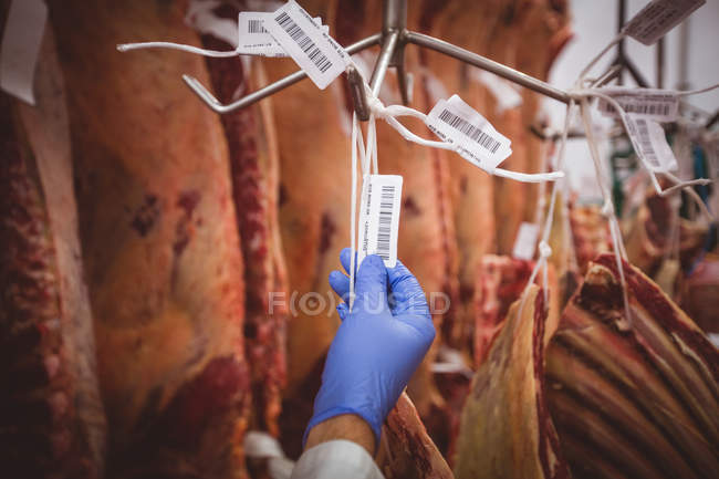 Mano di macelleria attaccare adesivi codice a barre sulla stringa in magazzino presso macelleria — Foto stock