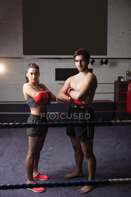 Portrait of male and female boxers standing with crossed arms on boxing ring and looking at camera — Stock Photo