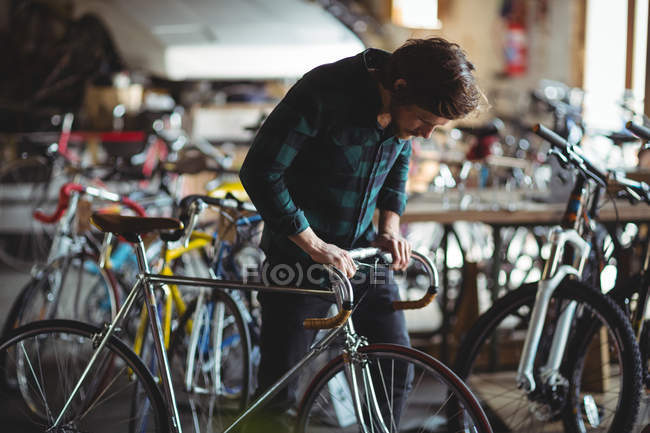 Mecânico examinando uma barra de alça de bicicleta na oficina — Fotografia de Stock