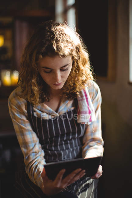 Beautiful waitress using digital tablet in workshop — Stock Photo