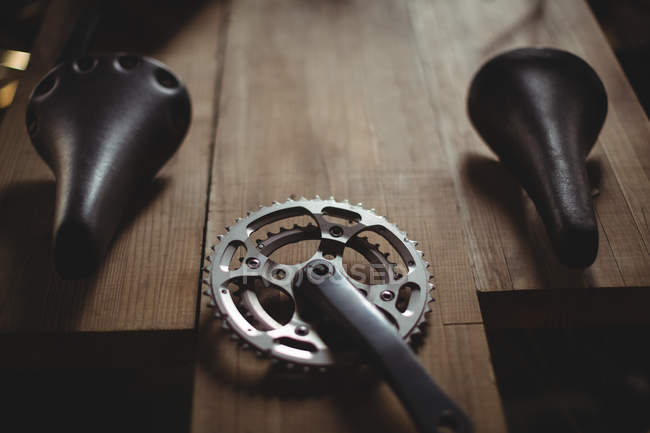 Close-up of bicycle gear and seat on wooden plank in workshop — Stock Photo
