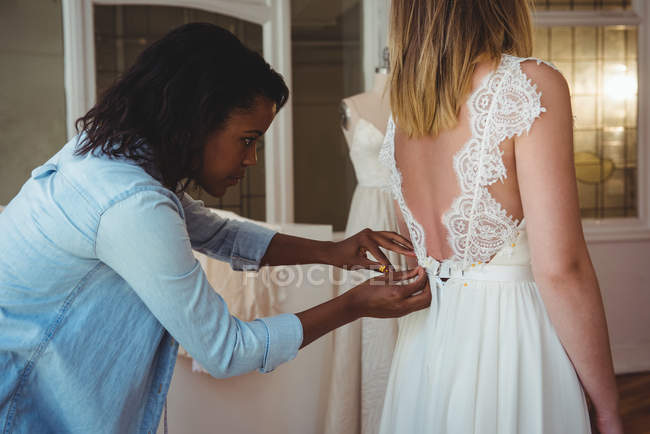 Donna che prova l'abito da sposa in uno studio con l'assistenza dello stilista — Foto stock