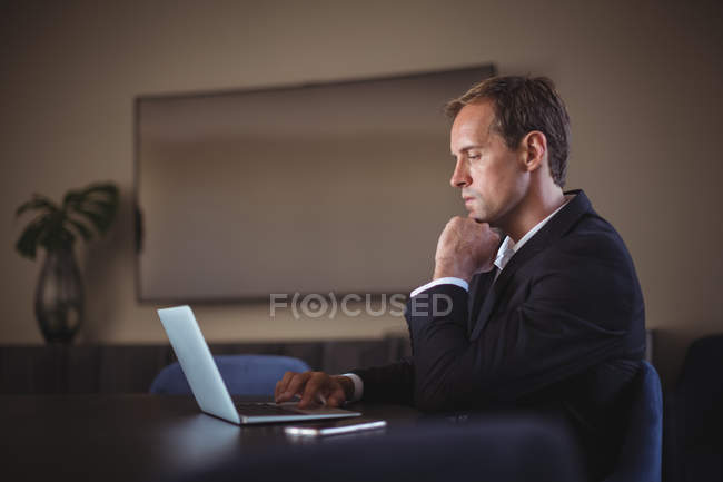 Thoughtful Business man using laptop at desk in office — Stock Photo