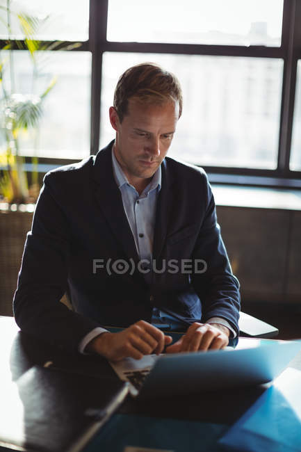 Concentrated businessman using laptop in office — Stock Photo