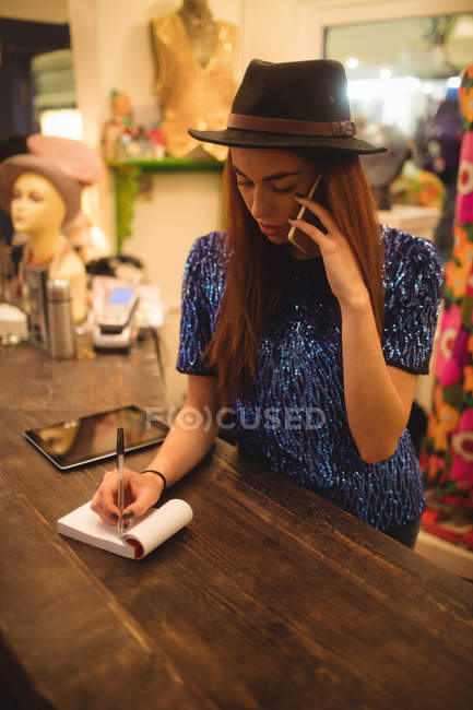 Female staff taking order on mobile phone in boutique store — Stock Photo