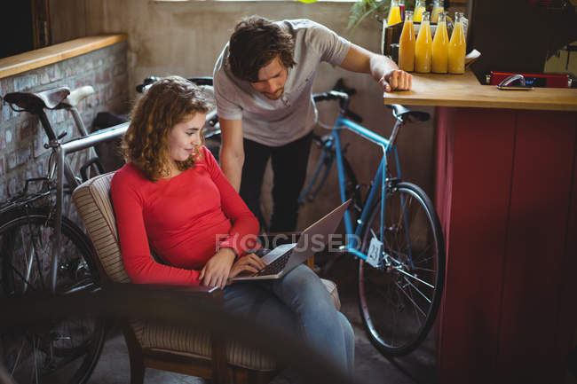 Pareja usando portátil en tienda de bicicletas - foto de stock