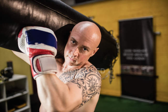 Retrato de boxeador carregando saco de perfuração no estúdio de fitness — Fotografia de Stock