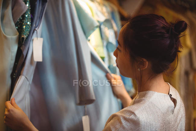 Donna che seleziona un abito da appendini al negozio boutique — Foto stock