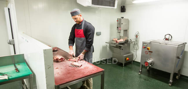 Butcher cutting pork ribs in butchers shop — Stock Photo