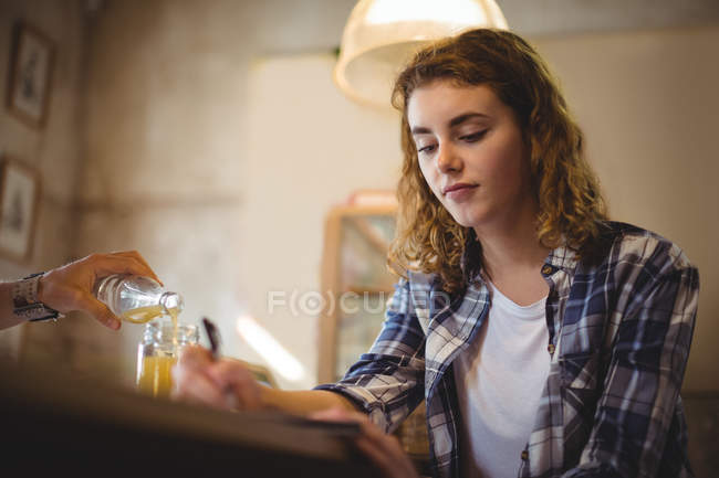 Beautiful mechanic sitting at counter and writing in dairy in workshop — Stock Photo