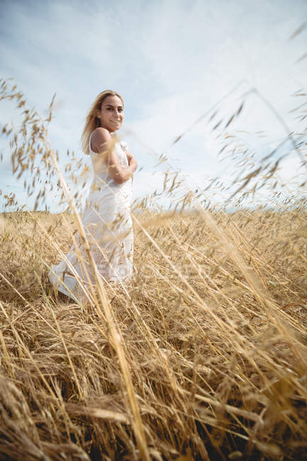 Selective focus of blonde woman standing in field and looking at camera — Stock Photo