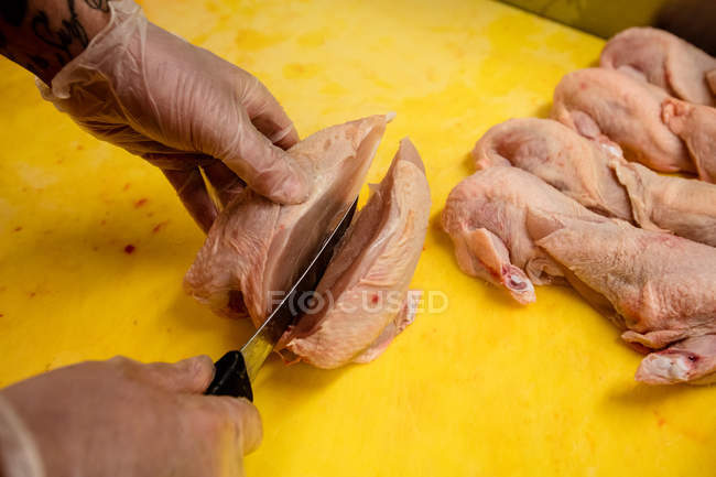 Mains de boucher hacher du poulet sur le comptoir de travail dans la boucherie — Photo de stock