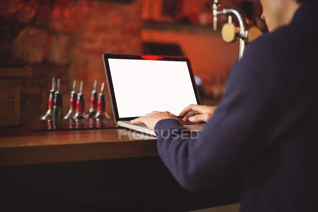 Hombre usando el ordenador portátil en el mostrador de bar - foto de stock