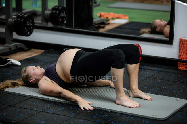 Mulher grávida realizando exercício de alongamento no ginásio — Fotografia de Stock