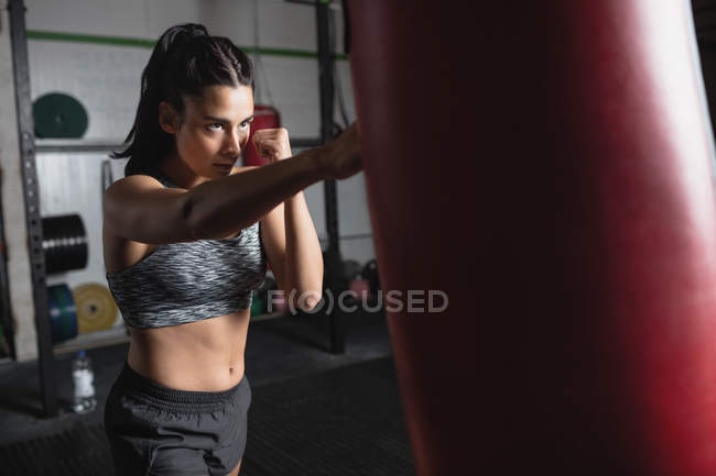 Selective focus of Female boxer practicing boxing with punching bag in fitness studio — Stock Photo