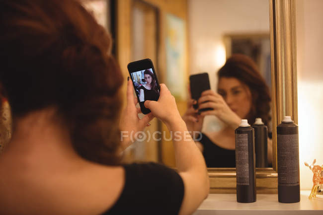 Mujer tomando selfie desde el teléfono móvil en el salón - foto de stock