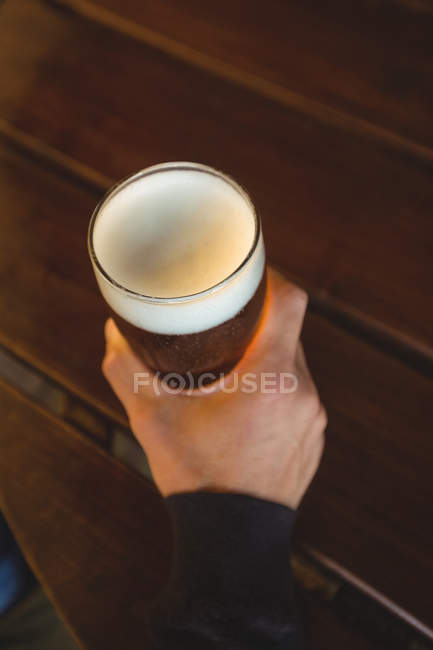 Man holding glass of beer at bar — Stock Photo