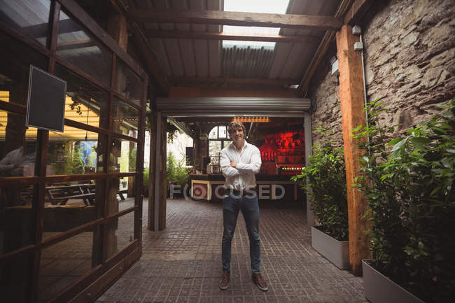 Porträt eines lächelnden Mannes, der mit verschränkten Armen in der Bar steht — Stockfoto