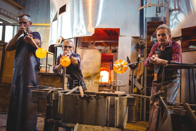 Squadra di soffiatori di vetro che modellano un vetro sulle soffiatrici nella fabbrica di soffiaggio del vetro — Foto stock