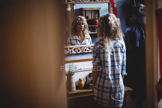 Красивая женщина смотрит в зеркало на домашний интерьер — стоковое фото