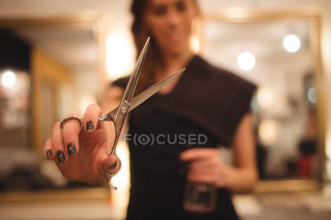 Female hairdresser holding scissors at saloon — Stock Photo