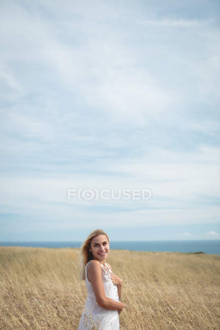 Portrait de femme blonde souriante debout dans le champ — Photo de stock