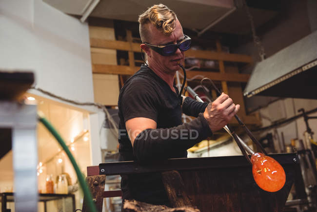 Glassblower shaping molten glass on marver table at glassblowing factory — Stock Photo