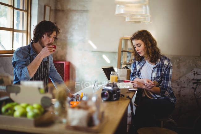 Mechanic and waiter having coffee at counter in workshop — Stock Photo