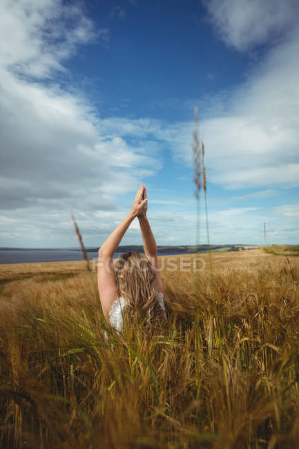 Donna con le mani alzate sopra la testa in posizione di preghiera in campo nella giornata di sole — Foto stock