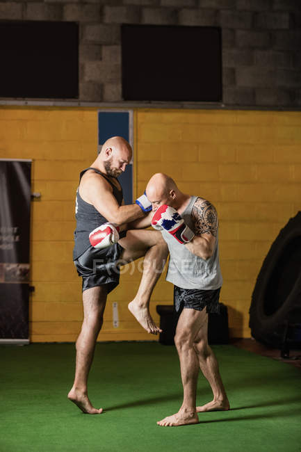 Vue latérale de deux boxeurs thaï forts pratiquant dans la salle de gym — Photo de stock