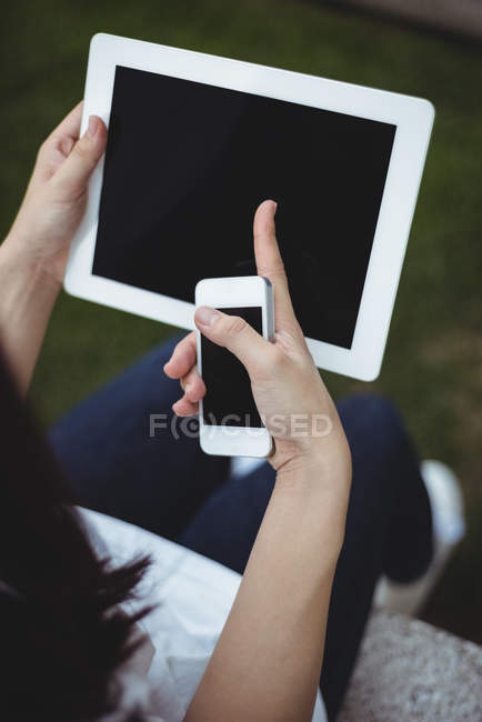 Крупный план женщины с использованием цифрового планшета и мобильного телефона — стоковое фото