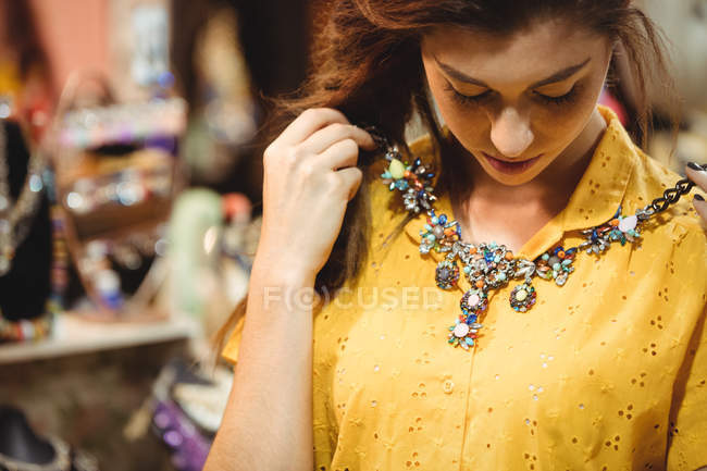 Woman wearing a vintage necklace in antique shop — Stock Photo