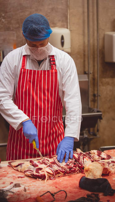 Metzger schneidet rotes Fleisch in Metzgerei — Stockfoto