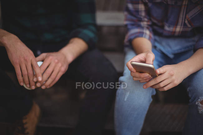 A meio da seção do casal sentado nas escadas e usando telefone celular — Fotografia de Stock