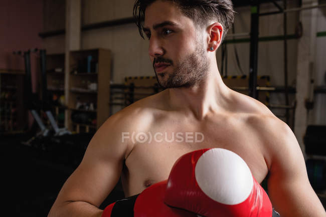 Portrait Boxer in boxing gloves looking away at fitness studio — Stock Photo