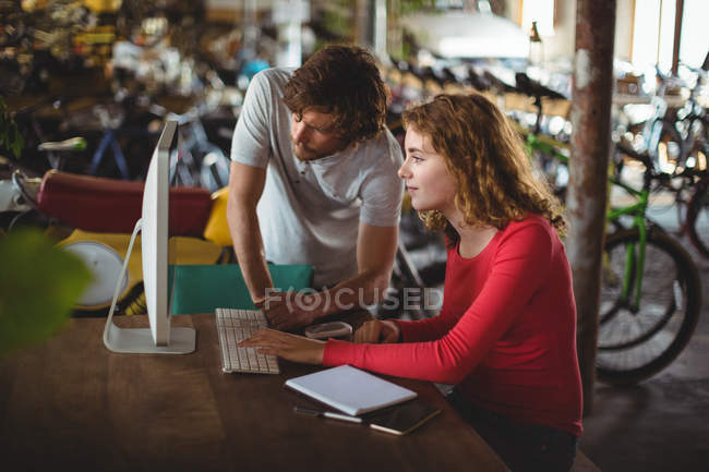 Casal usando computador na mesa n loja de bicicletas — Fotografia de Stock
