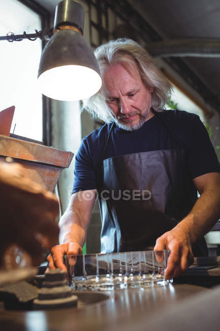 Зрелый стеклодув, работающий на стеклодувном заводе — стоковое фото