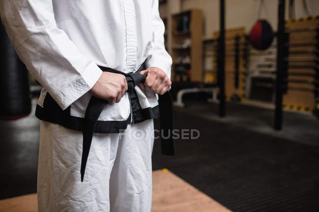 Sección media del hombre en kimono karate de pie en el gimnasio - foto de stock