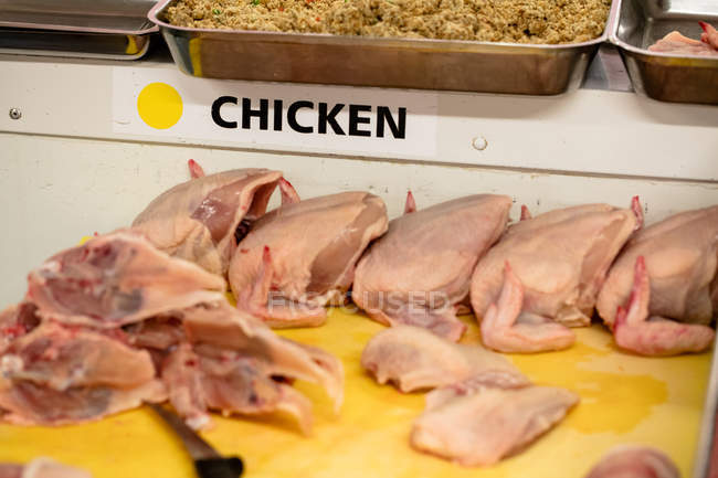 Pollo crudo mantenido en el mostrador de trabajo en la carnicería - foto de stock
