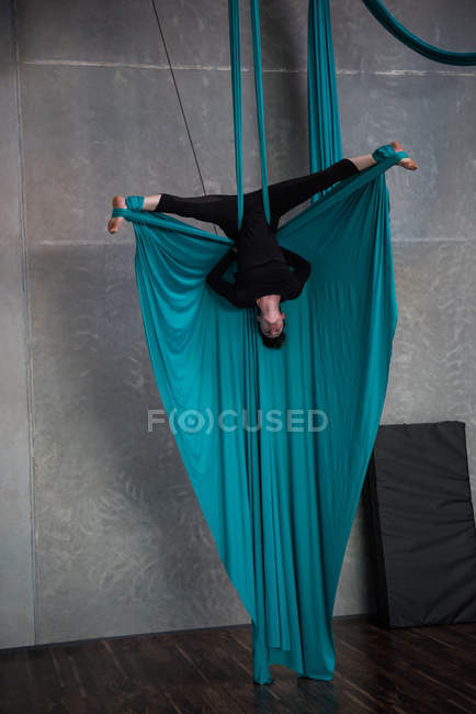 Gymnast exercising on blue fabric rope in fitness studio — Stock Photo
