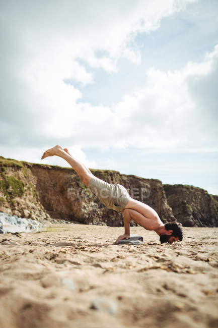 Hombre realizando yoga en la playa - foto de stock