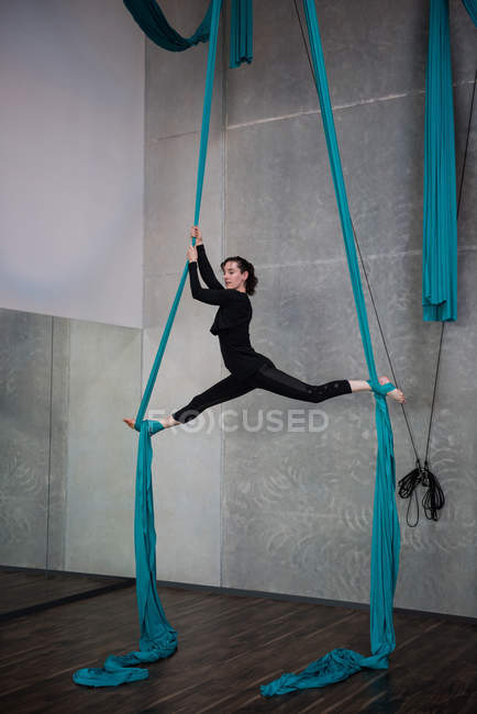 Гимнаст тренируется на синей веревке в фитнес-студии — стоковое фото