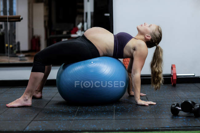 Schwangere macht Dehnübungen auf Fitnessball im Fitnessstudio — Stockfoto
