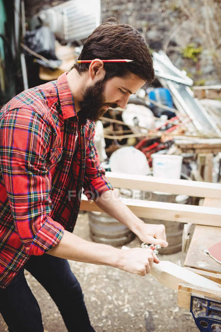 Uomo che utilizza uno strumento palmare per levigare e livellare la superficie di una tavola in cantiere — Foto stock