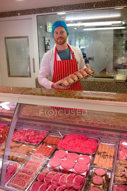 Ritratto di macellaio in piedi al banco di carne in macelleria — Foto stock