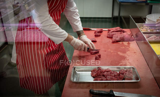 Mid section of butcher chopping red meat at butchers shop — Stock Photo