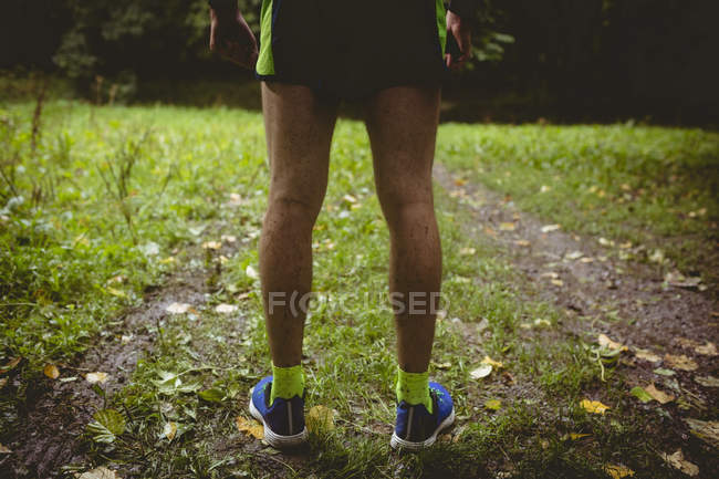 Low section of athlete standing in forest — Stock Photo