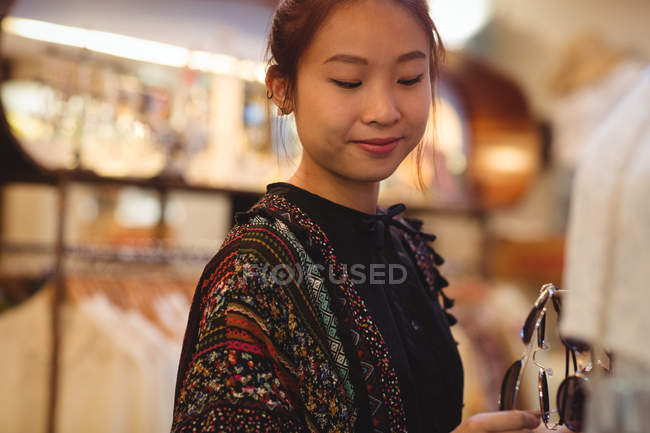 Stylish woman selecting sunglasses in a antique jewellery shop — Stock Photo