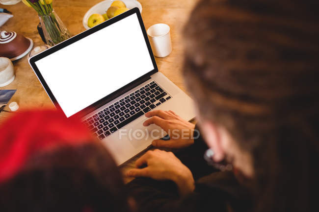 Imagen recortada de la pareja usando el ordenador portátil en la mesa - foto de stock