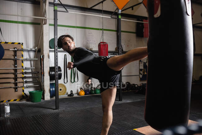 Vista laterale del Boxer maschile che pratica boxe con sacco da boxe in palestra — Foto stock